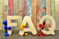 FAQ-Symbol — Buchstaben FAQ aus Holz mit Spielfiguren, symbolisiert häufige Fragen